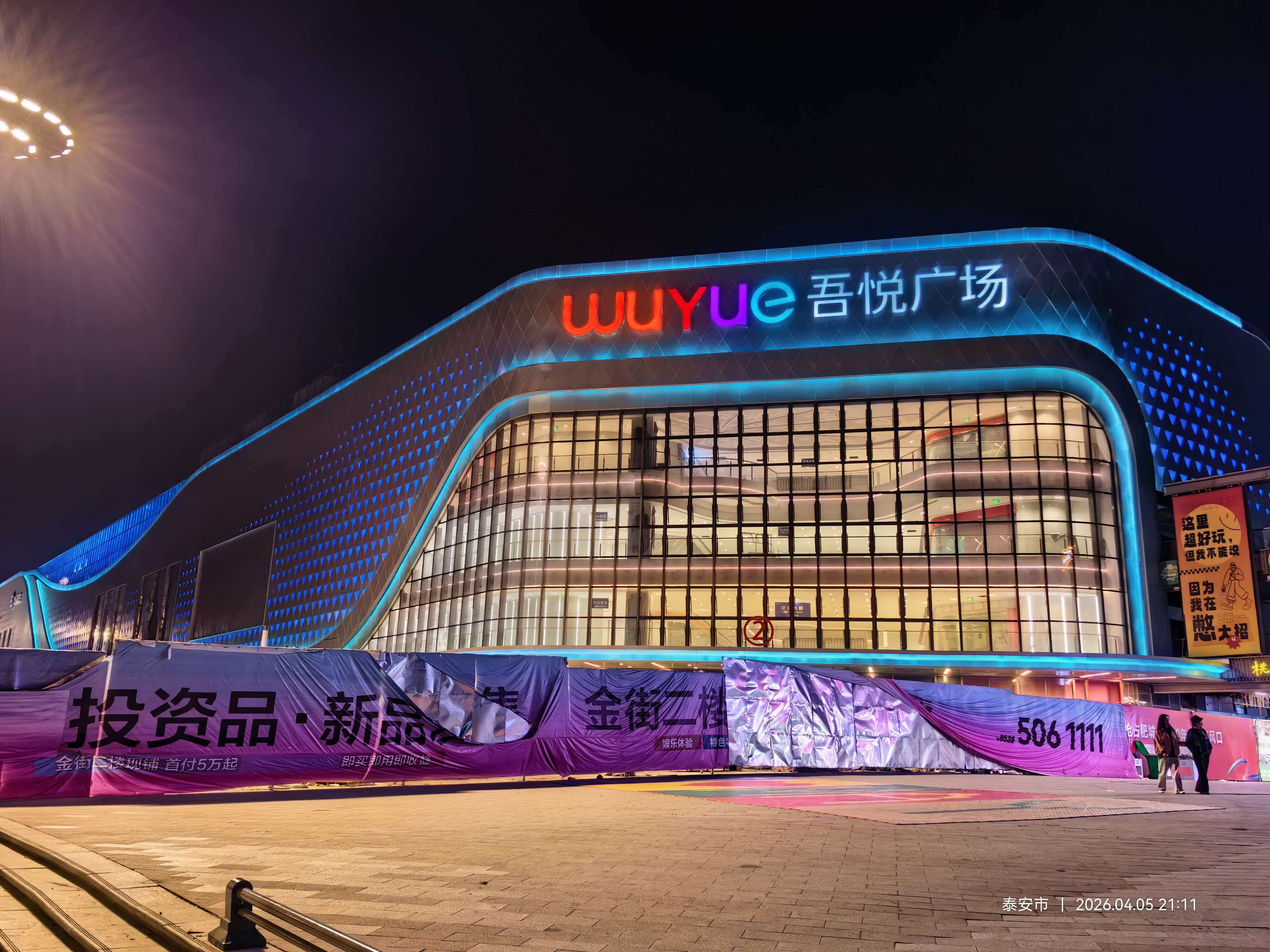 Lối vào chính của Feicheng Wuyue Plaza với biển hiệu thương hiệu đầy màu sắc của LNJAMI và hệ thống chiếu sáng mặt tiền kiến trúc vào ban đêm.