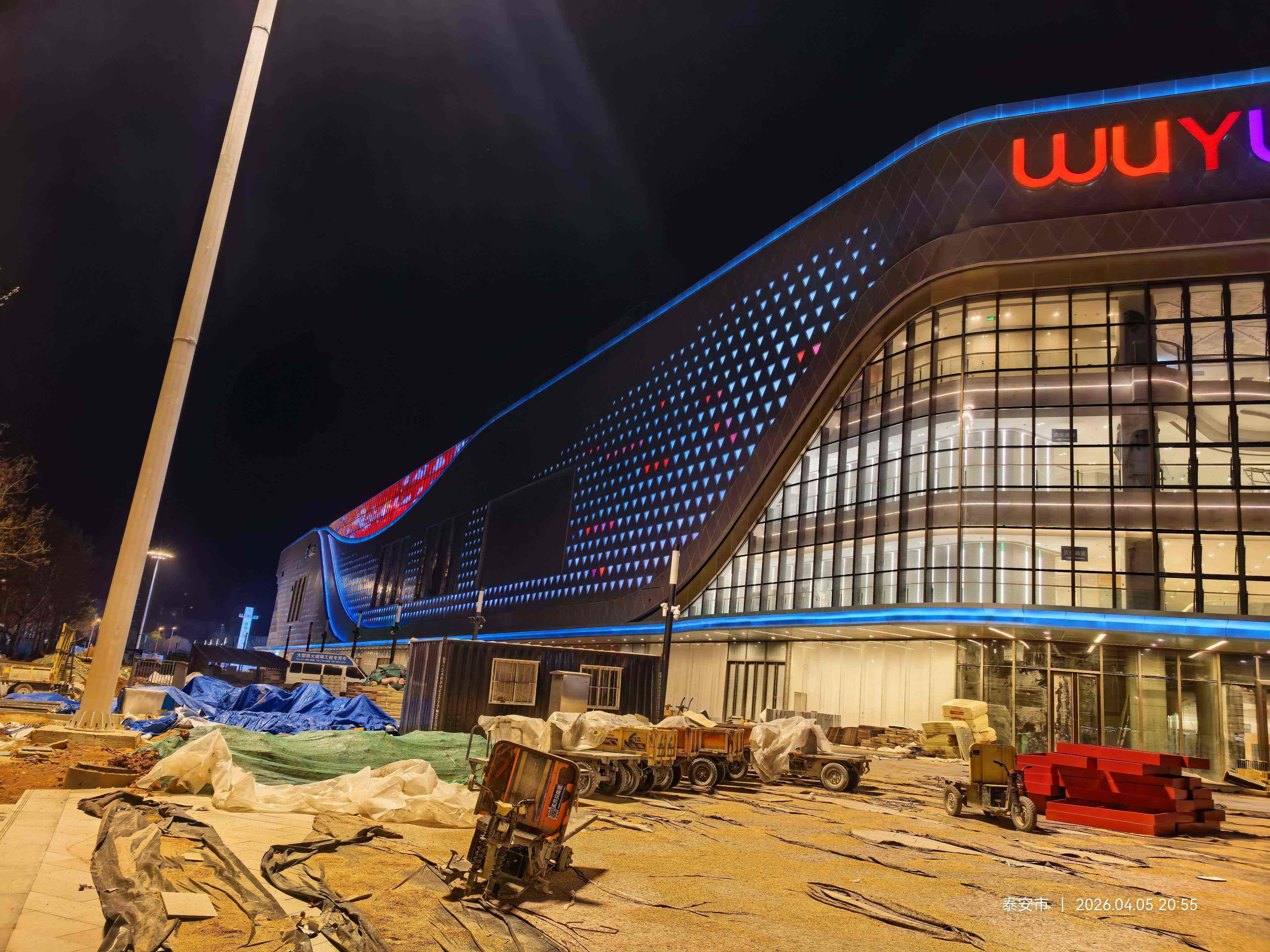Lối vào chính của Feicheng Wuyue Plaza với biển hiệu thương hiệu đầy màu sắc của LNJAMI và hệ thống chiếu sáng mặt tiền kiến trúc vào ban đêm.